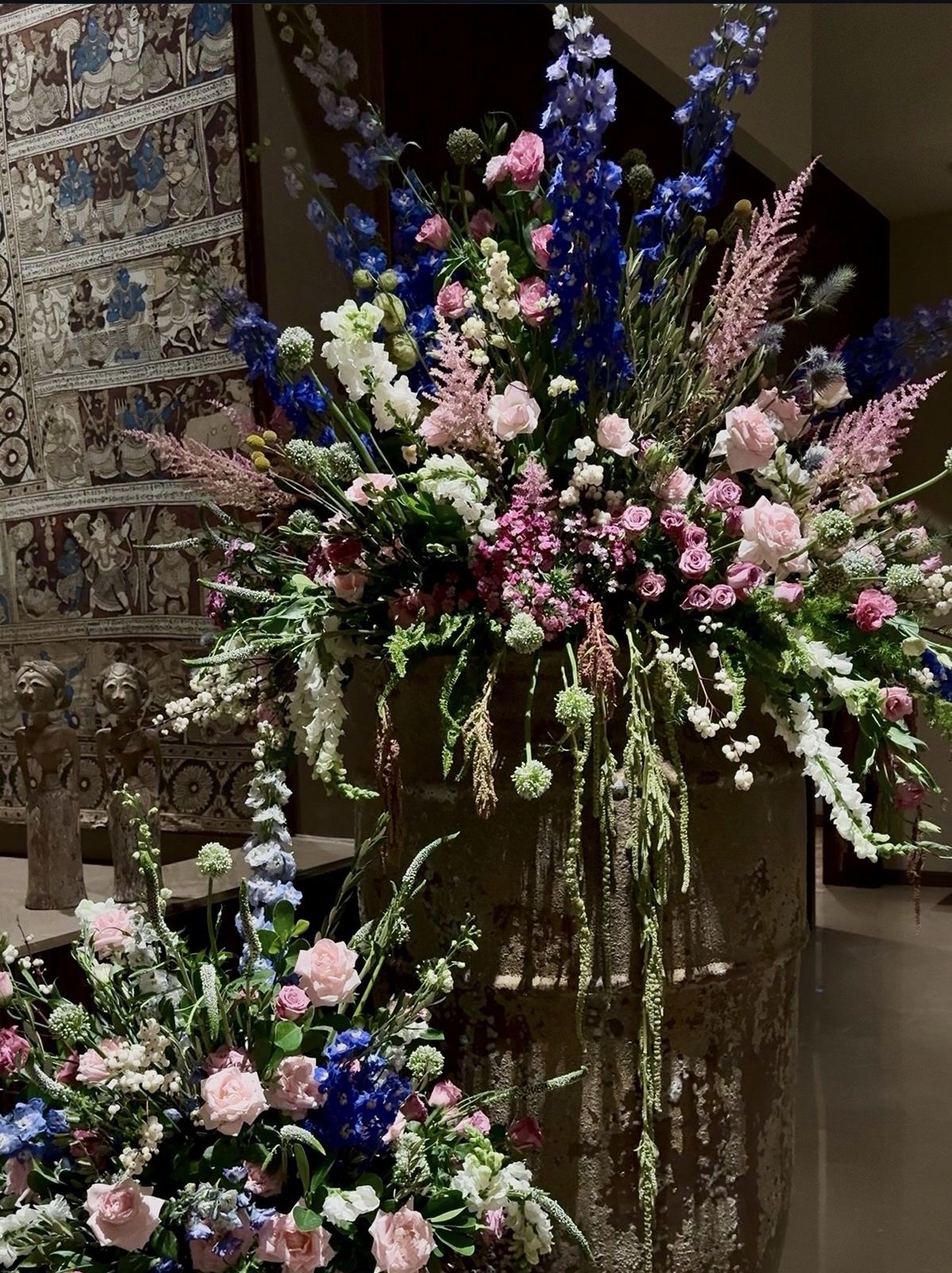 Tall arrangement of delphinium, pink roses and astilbe in a stone urn